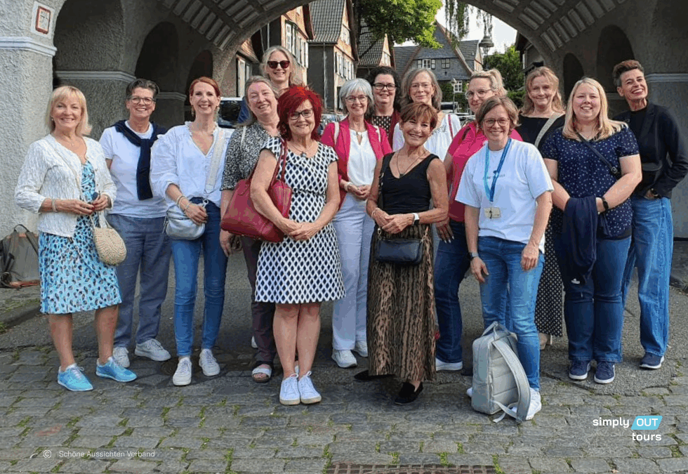 Gruppenfoto der Mitfrauen des Netzwerks Schöne Aussichten bei einer geführten Tour durch die Margarethenhöhe in Essen unter dem markanten Torbogen zur Siedlung Margarethenhöhe